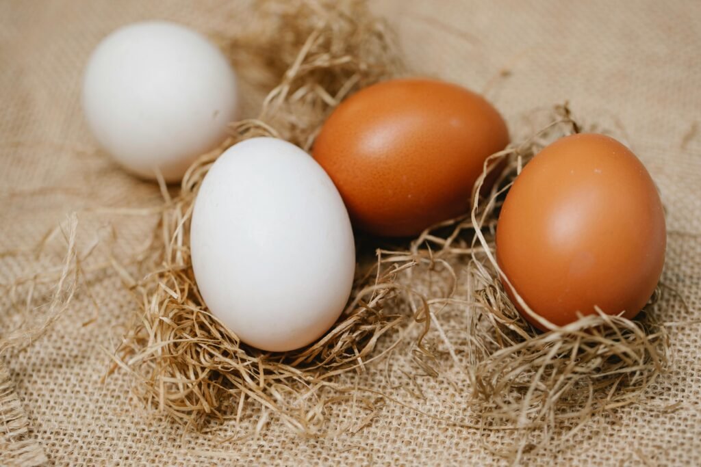 Close-up of white and brown eggs resting on rustic straw and burlap, showcasing organic simplicity.